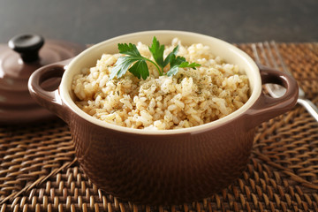 Bowl with brown rice on wicker mat