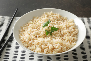 Plate with brown rice on table