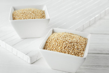 Bowls with quinoa seeds on white wooden table