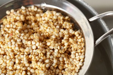 Sieve with quinoa seeds in saucepan, closeup