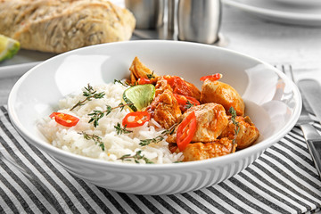 Plate with chicken tikka masala and rice on white table