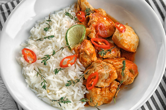 Plate with chicken tikka masala and rice in white bowl