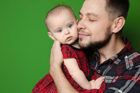 Father posing with cute baby daughter on color background