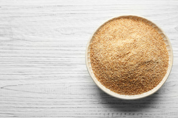 Small bowl of bread crumbs on wooden background