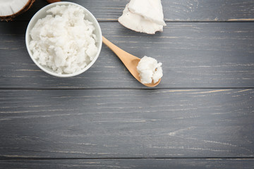 Bowl and spoon with fresh coconut oil on wooden grey background