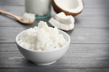 Bowl with fresh coconut oil on wooden grey background