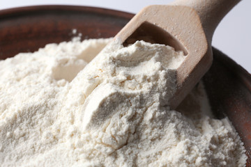 Bowl with flour and wooden scoop, closeup