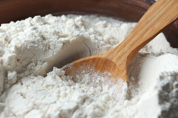 Wooden spoon in flour, closeup