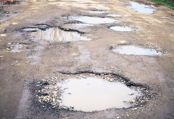 Road destroyed after winter. Puddles in the pits in the road.