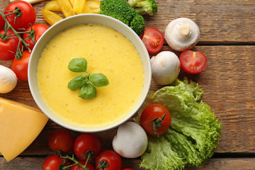 Appetizing composition of creamy cheese in bowl and fresh vegetables on wooden background