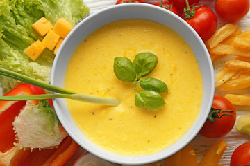 Appetizing composition of creamy cheese in bowl and fresh vegetables on wooden background