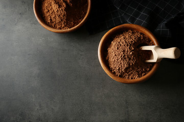 Bowls with cocoa powder on grey background