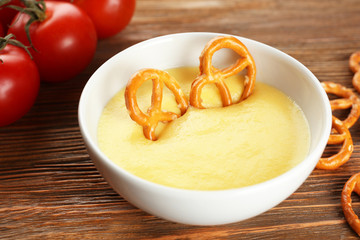 Dipping pretzel into bowl with cheese sauce on dining table