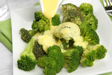 Pouring broccoli with cheese sauce, closeup
