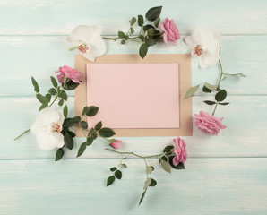 Floral frame consists of roses and orchid flowers and empty paper