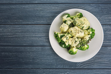 White plate of delicious broccoli with cheese cream on wooden background