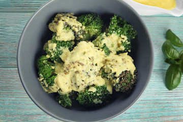 Grey bowl of delicious broccoli with cheese cream on wooden background