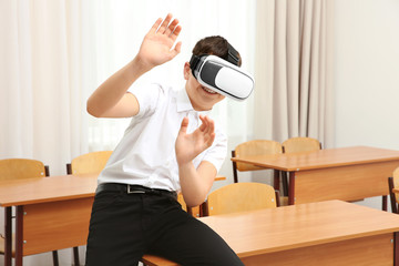 Fototapeta na wymiar Boy having fun with virtual reality headset in classroom