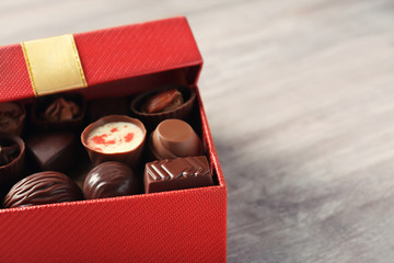 Gift box with delicious candies on wooden background