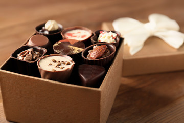 Gift box with delicious candies on wooden background