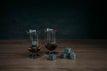 Stones for cooling whiskey and glases tulup on dark wooden background