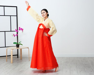 Beautiful young woman in Korean traditional costume dancing at home
