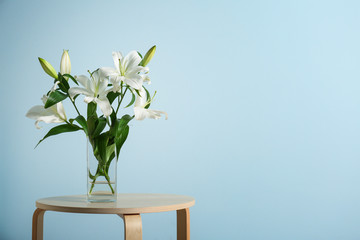 Beautiful white lilies in vase on stool