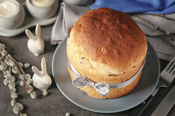 Plate with Easter cake and rabbits on grey table