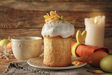 Plate with Easter cake and cup on wooden background