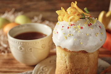 Plate with Easter cake and cup on wooden background