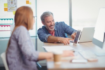 Obraz premium Male and female executive discussing over digital tablet