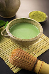 Still life with Japanese matcha accessories and green tea in bowl
