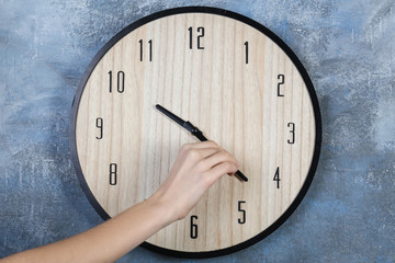 Female hand change time on big wall clock