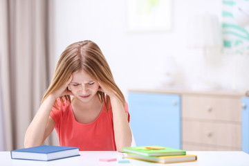 Cute girl suffering from headache while doing lessons at home