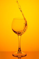 Splash of water in a glass on yellow