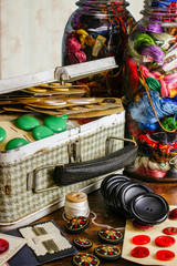 Vintage buttons in an old metal lunchbox on a table with thread and needls