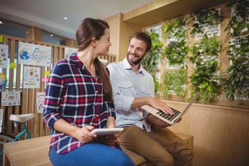 Graphic designers interacting while using laptop