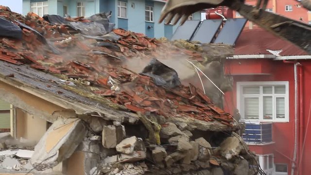 Tearing down the old building on construction site. Some substances as dust in concrete can cause health concerns due to toxicity. Excavator turning homes into rubble and dust fills the air