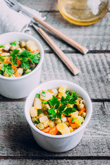 Healthy Vegetable salad with potato,carrot,pears and green onion in a white bowl on wooden table. Vegetarian food content. 