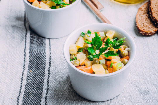 Healthy Vegetable salad with potato,carrot,pears and green onion in a white bowl on table. Vegetarian food content. 