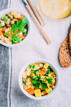 Healthy Vegetable salad with potato,carrot,pears and green onion in a white bowl on table. Vegetarian food content. 