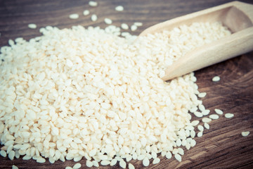 Vintage photo, Heap of sesame seeds with wooden scoop on board
