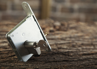 key and lock on a wooden table bg