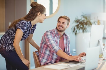 Graphic designers interacting while working on personal computer