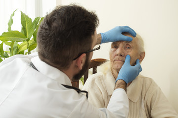 Lekarz bada oczy, spojówki bardzo starej kobiety. Lekarz geriatra podczas badania.