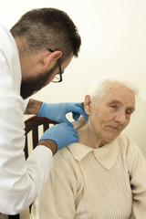 Lekarz geriatra podczas badania. Lekarz bada zmiany na skórze u starej kobiety. - obrazy, fototapety, plakaty