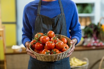 Vendor holding a basket of tomatoes