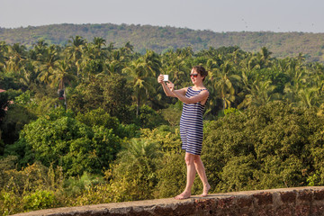 Fototapeta premium Young woman is making a selfie photo from a mobile phone, Goa, India