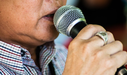 close up senior man holding microphone