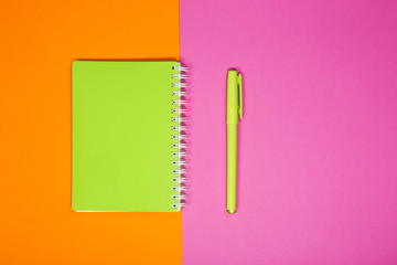 Green notebook and pen on a colored background	